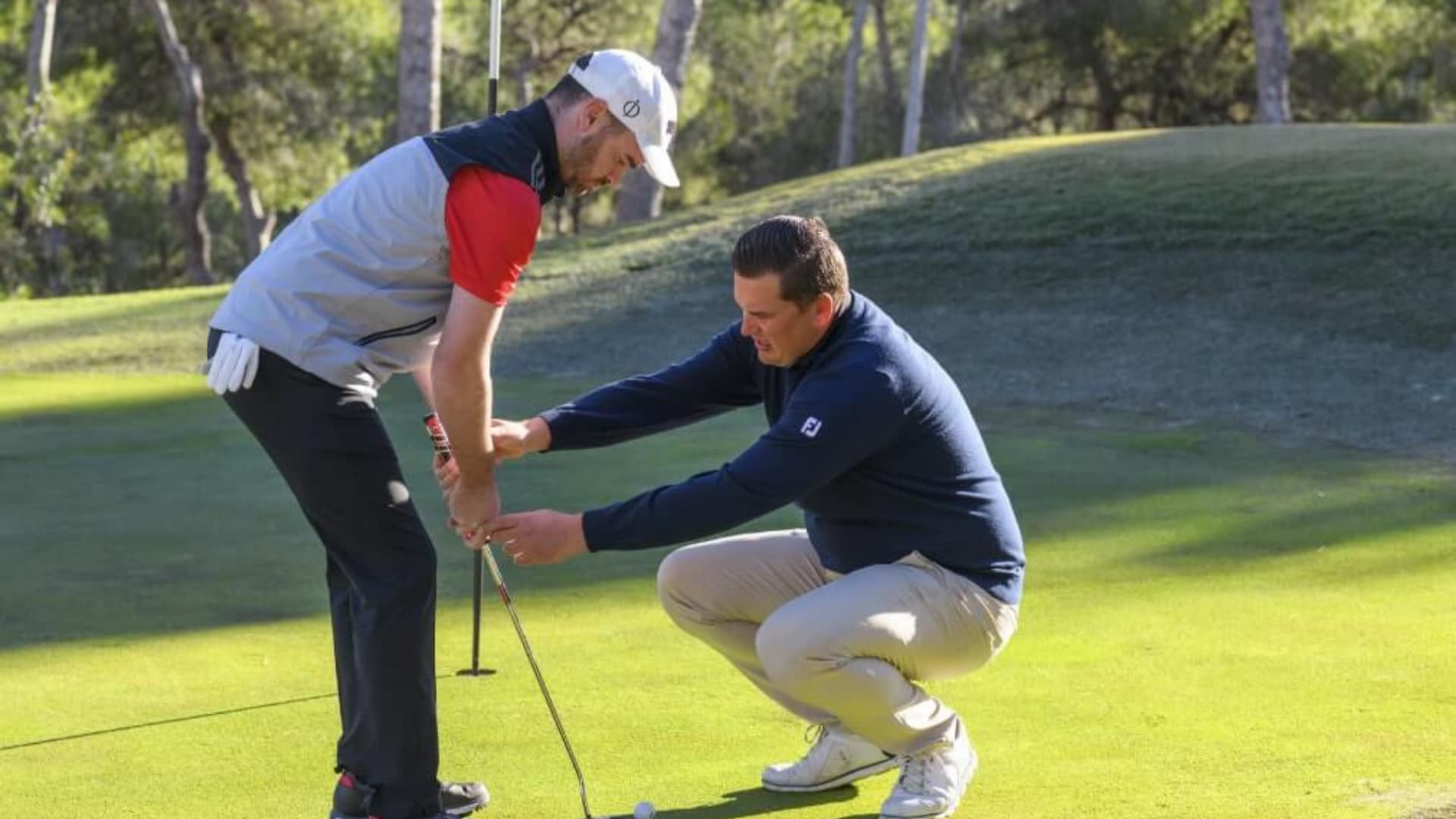 Golf academy teacher helping a golfer student